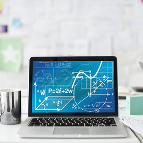 A laptop with mathematical formulas stands on a white desk next to a cup, pens and sheets of paper.